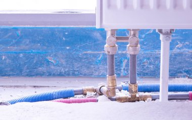 Alttaki plastik borularla birbirine bağlı beyaz metal radyatör