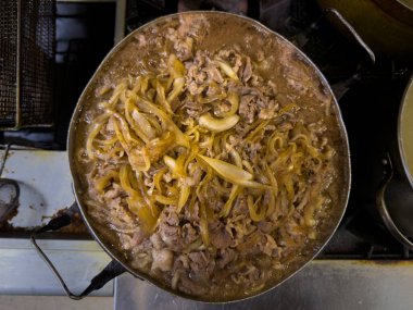 Bol soslu sığır eti ve soğanlı doyurucu bir tava. Aile yemekleri, ev yemekleri ve sıcak yemekler için ideal..