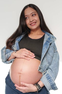 İyi durumdaki genç ve güzel bir kadın karnının üstünde el ele tutuşuyor. Mutlu anne hamilelik boyunca bebek bekliyor..