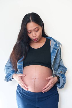 Hamilelik, aşk, aile ve insan konsepti. Hamile bir kadının elini karnına koyup kalp hareketi yapması.