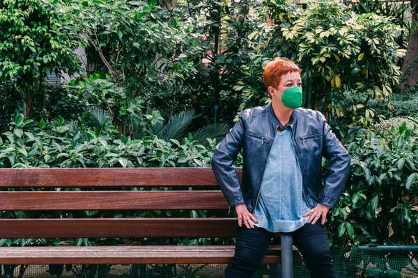 Middle-aged red-haired woman with facial mask in the city