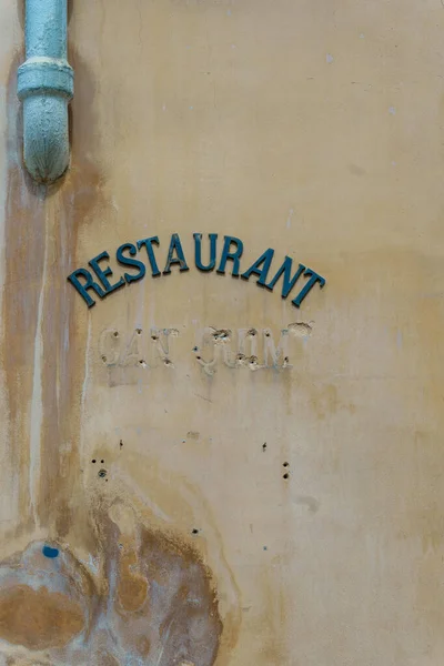 Old metal restaurant sign on a weathered wall
