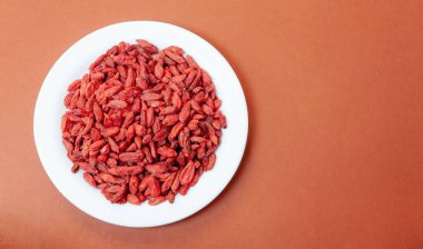 Kahverengi arka planda beyaz bir tabakta kurumuş böğürtlen sürüsü.