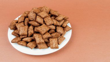 Çikolata dolgulu bir avuç kuru kahvaltı yastığı, açık kahverengi arka planda mesaj için yer var.