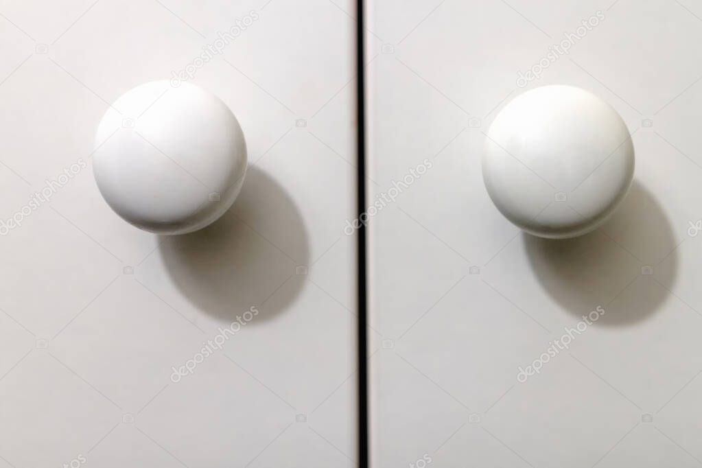 two round wooden carved handles on white cabinet doors