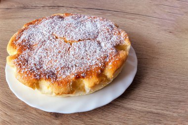 fırında peynirli kek, kül tabağının üzerinde beyaz bir tabakta.