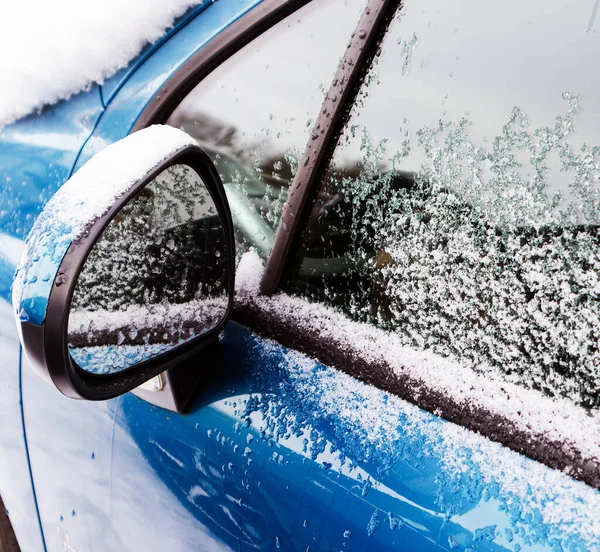 Kışın mavi araba aynası ve pencere camları karlı ve donmuş olur.