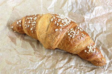 Katlanmış kağıttan bir yüzeyde pişmiş kruvasan, üst görünüm.