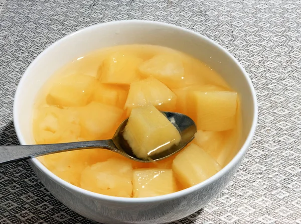 Beyaz bir kasede çay kaşığıyla konserve ananas.