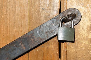 Evin bodrumunda eski ahşap bir kapının üzerinde metal bir kilit var.