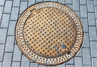 Asfalt blokları arasında kanalizasyon kapağı, üst görünüm