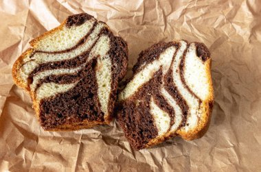 Yiyecek kağıdının yüzeyinde iki parçaya bölünmüş çikolatalı kek, yukarıdan görünüyor.