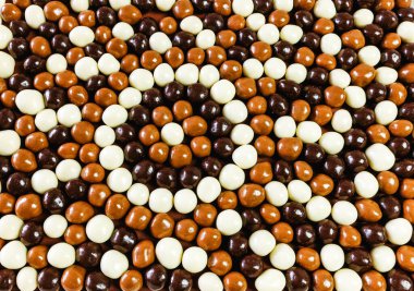 Çeşitli renkli çikolata toplarının arka planı bir mozaik içinde, yukarıdan bir manzara olarak serilmiştir.