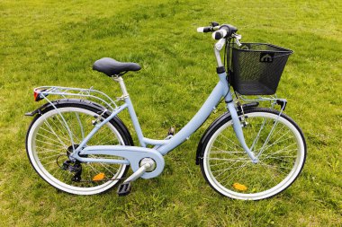 Baharda asılı bir çantayla çayırda duran bir kadın bisikleti.