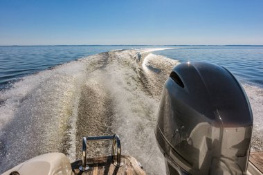 Güneşli bir yaz gününde gölde yelken açan bir tekne denizde derin izler bırakır.