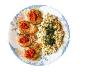 Bir tabakta domuz fileto bifteği ve beyaz arka planda bitki karışımı.