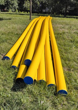 Yeraltı elektrik tesisatını örtmek için yazın çayırdaki sarı koruyucu borular yığını.