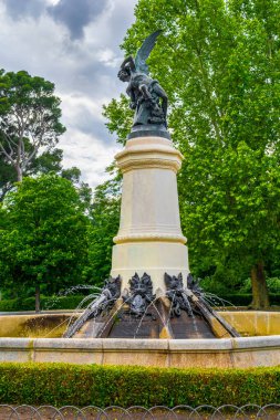 El Retiro Parkı 'ndaki Düşmüş Melek heykeli kara bulutlu bir gökyüzü tarafından çerçevelenmiştir.