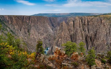 Gunnison Kanyonu 'nun çatlakları Gunnison Point' teki renkli yeşillik ve mavi gökyüzü ile tezat oluşturuyor.