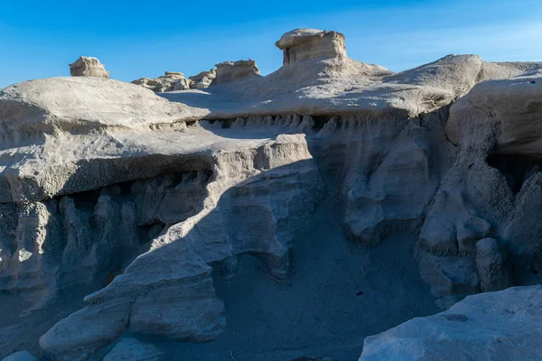 Mavi gölge ve mavi gökyüzü Bisti Badland kumtaşı tepelerini daha da güçlendirmek için güneş ışığıyla tezat oluşturuyor.