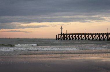Batı Flanders, Belçika 'daki Blankenberge limanının girişindeki ahşap iskelenin arkasında güzel bir günbatımı..