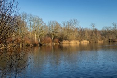 Doğu Flanders, Belçika 'daki Geraardsbergen yakınlarındaki Gavers Eğlence Alanı' ndaki insan yapımı Gaverplas 'ın (Gaver Gölü) görüntüsü. Göl, halka açık bir dinlenme alanının bir parçasıdır. Boşluğu kopyala.