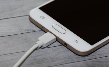 Gri arkaplanda şarj edilen telefon fotoğrafları.