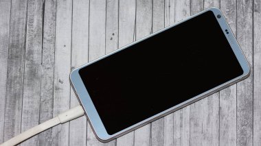 Gri arkaplanda şarj edilen telefon fotoğrafları.