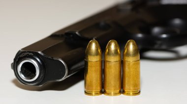 Siyah tabanca ve mermilerin fotoğrafları.