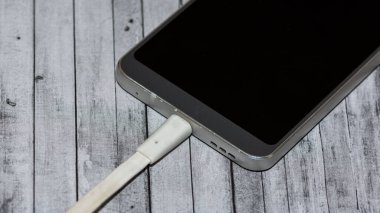 Gri arkaplanda şarj edilen telefon fotoğrafları.