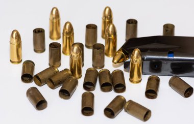 Siyah tabanca ve beyaz arka planda mermilerin fotoğrafı.