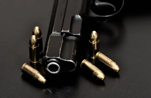 photo of a black pistol and bullets on a black background