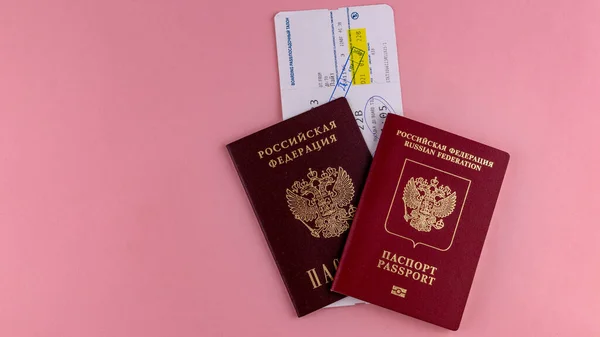 Gül arka planında uçak bileti olan iki pasaport.