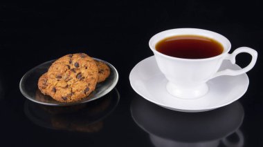 Siyah arka planda yulaf ezmeli beyaz çay.