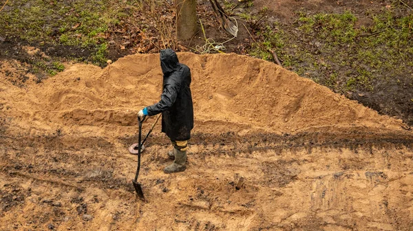 Metal dedektörlü bir işçi arkeolojik alanda değerli eşyalar arıyor.