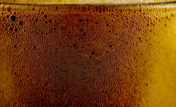 foam of dark beer in a glass glass, macro photography, backgrounds, textures