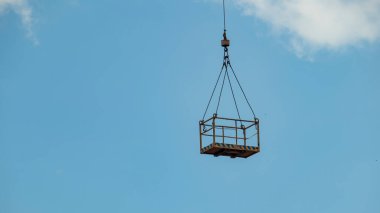 Mavi gökyüzüne karşı bir kule vinci, bir inşaat beşiği ile