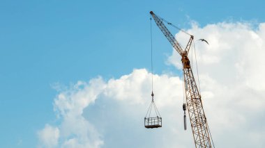 Mavi gökyüzüne karşı bir kule vinci, bir yapı beşiği, arka planlar