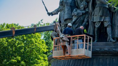 Tamir edilmeden önce bir inşaat beşiğindeki anıtı bir işçi ve restoratör inceler.