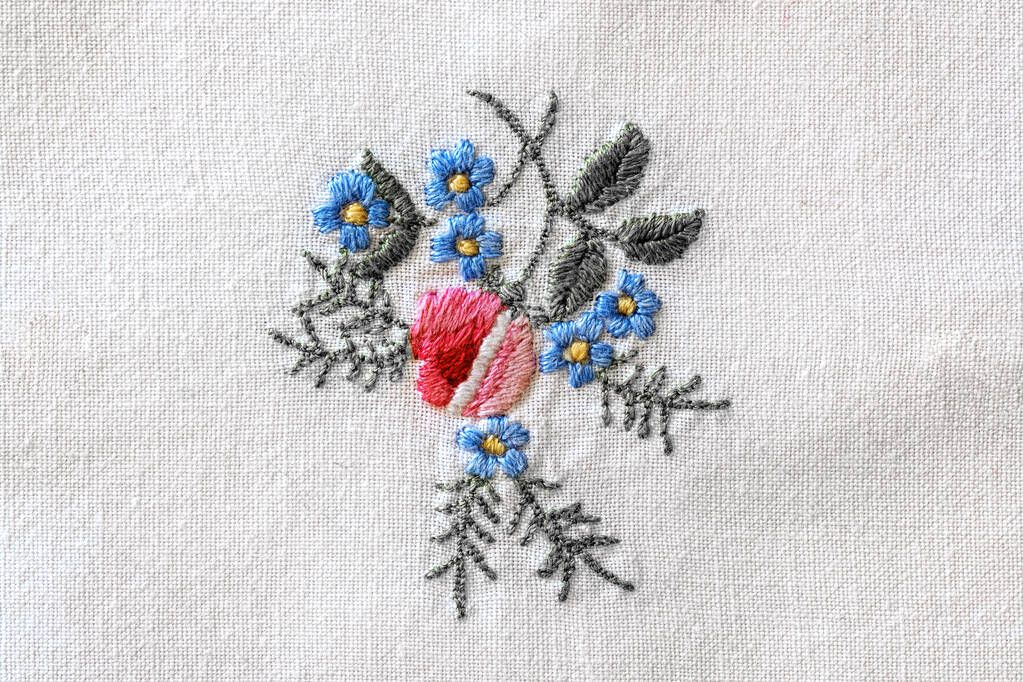 close up of a colorful flower embroidery on old white tablecloth
