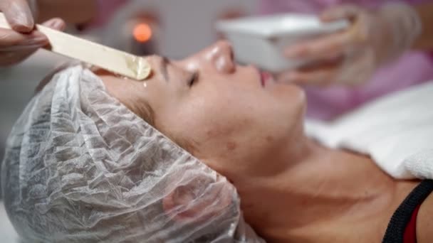 Kvinnlig kosmetolog förbereder sig för laserföryngring och ansiktshårborttagning av kvinna liggande på medicinsk soffa i skönhetssalong. Kosmitologi, epilering och spa koncept. Kropp och hudvård. Närbild — Stockvideo