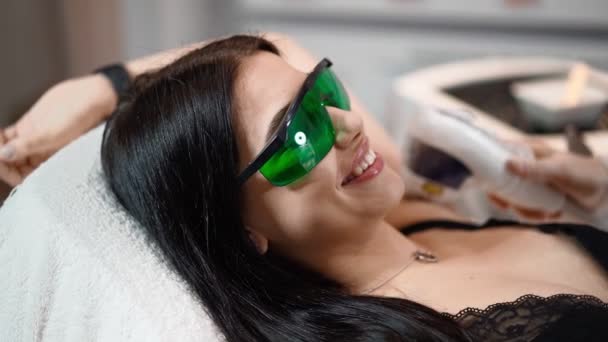 Žena kosmetička dělat podpaží laser odstranění chloupků atraktivní sexy žena ležící na gauči a usmívá se v salonu krásy. Kosmitologie, epilace a lázeňský koncept. Péče o tělo. Zpomal. Detailní záběr — Stock video