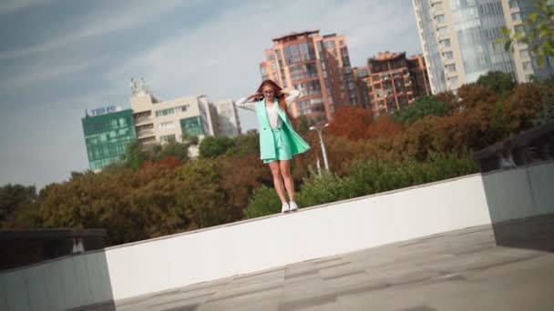 유행하는 청록색 양복을 아름답고 여자는 도시의 배경에 재미있는 도약적 행복이다 — 비디오