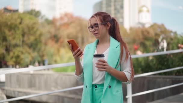 Gözlüklü Turkuaz Ceketli Güzel Bir Kadını Gülümsüyor Sokakta Cep Telefonuyla — Stok video