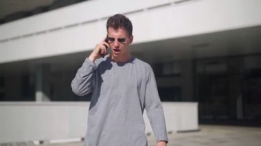 Güneş gözlüklü yakışıklı adam telefonda konuşuyor ve öfkeyle diğer kişiye bağırıyor. Adam akıllı telefondan konuşurken kavga ediyor. İş Merkezi 'nin yanındaki Urban Park' ta sahne çekimi. Yavaş çekim.