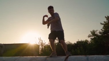 Mutlu adam güzel bir günbatımının arka planında komik bir şekilde dans ediyor. Yavaş çekim