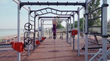 Mor spor eşofmanlı genç atletik kadın şehir parkında karın kasları egzersizi yapıyor. Spor ve açık havada egzersiz. Yavaş çekim