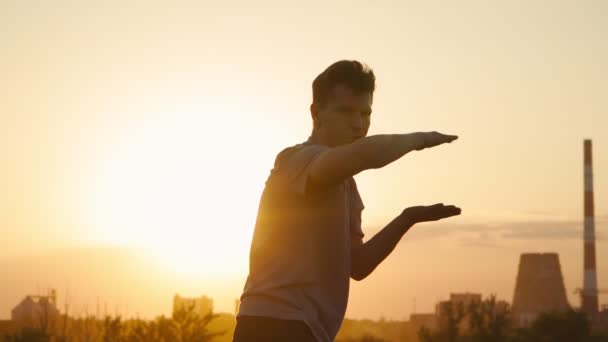 Silhouet van een man die vechtsporten beoefent op de achtergrond van een prachtige zonsondergang. Hij traint Tai Chi en karate. Kunst van zelfverdediging. Langzame beweging — Stockvideo