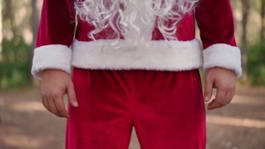 Koruyucu maske takmış, Noel Baba kostümü giymiş bir adam ormanda tek başına duruyor. Coronavirus ve Christmas. Karantina sırasında yeni yıl. Yavaş çekim