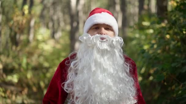 En seriös kille klädd i jultomtedräkt går episkt genom skogen. Julen. Nytt år. Långsamma rörelser — Stockvideo